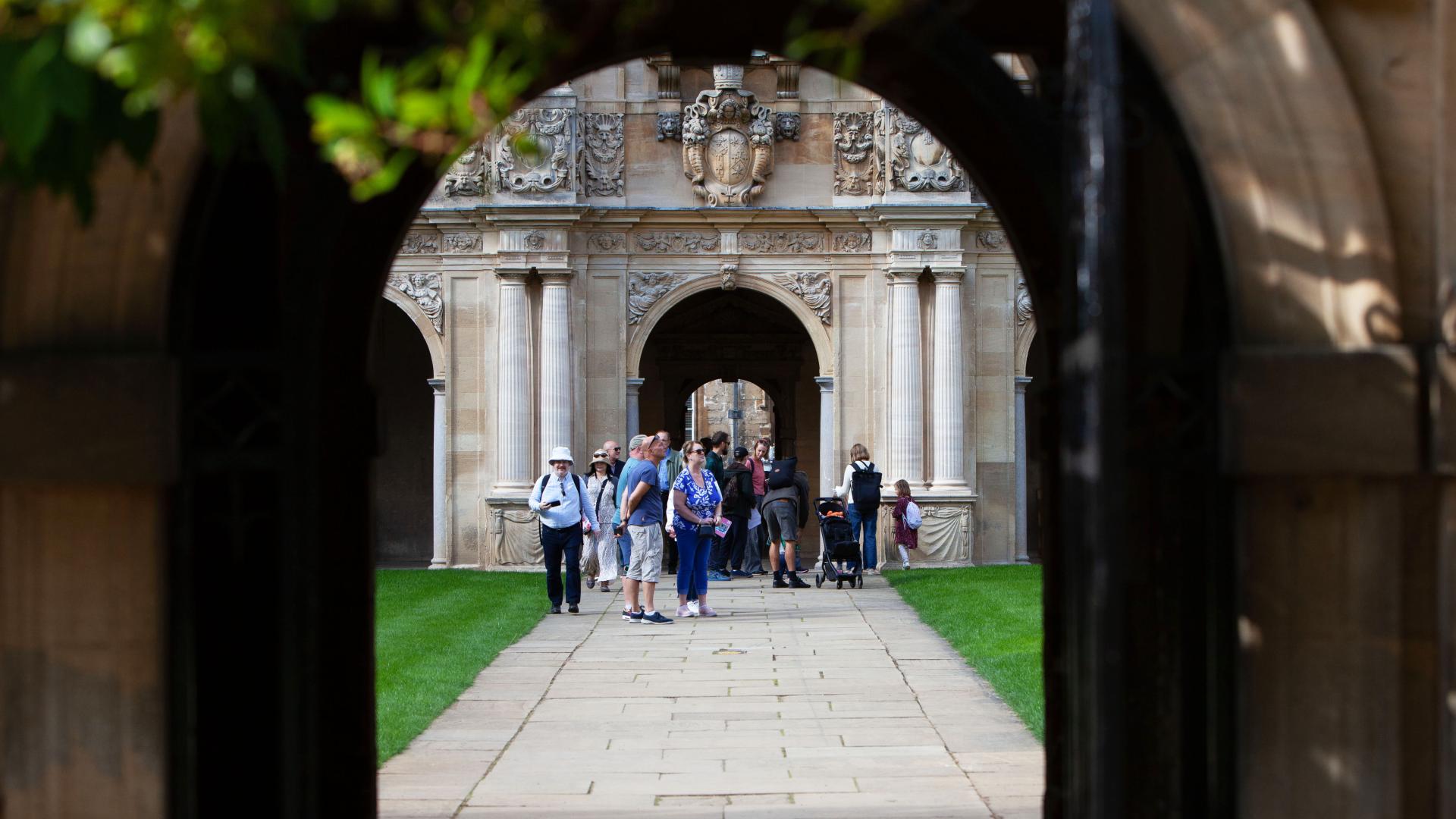 A group of visitors walk through a seventeenth-century quadrangle of an Oxford college.