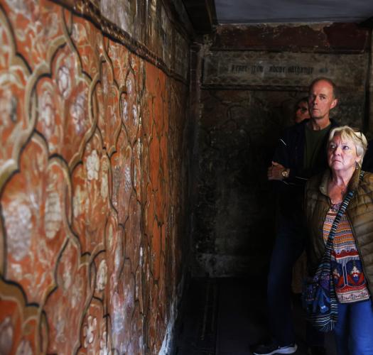 Two people looking at the wall paintings at the painted room