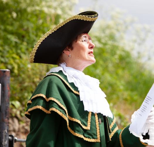 Town crier reading in front of greenery