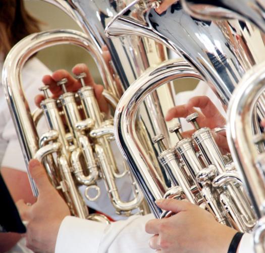 Close-up photograph of three brass instruments being played.
