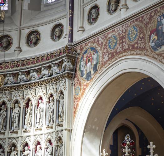 Image of a church interior with wall paintings and a sculpted reredos.