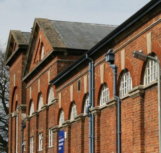 Photograph of a red brick building with semi-circle shaped white windows and a blue sign.