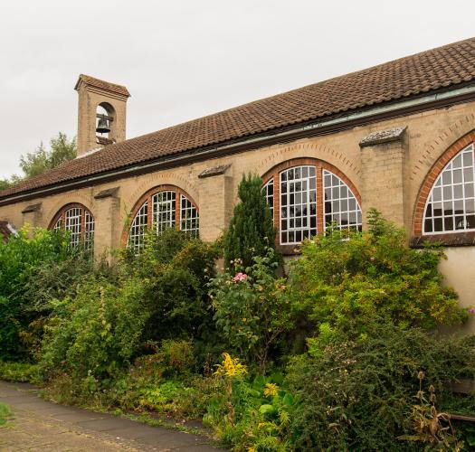 The side view of a one-storey church with semicircular windows and a small bell turret.