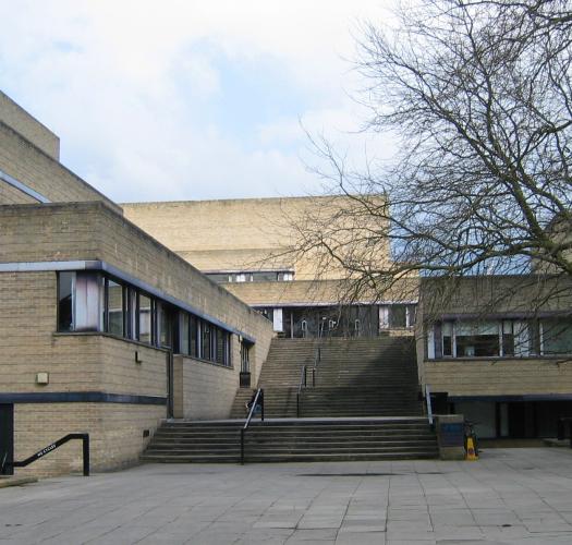 A modern brown brick building with rectangular wings and a long central staircase.