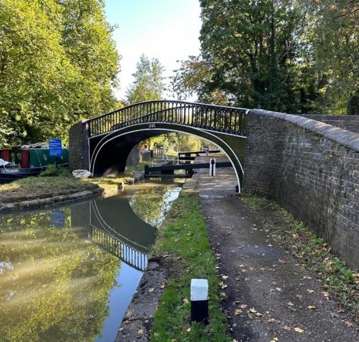 A bridge over a canal with towpaths and trees on either side.