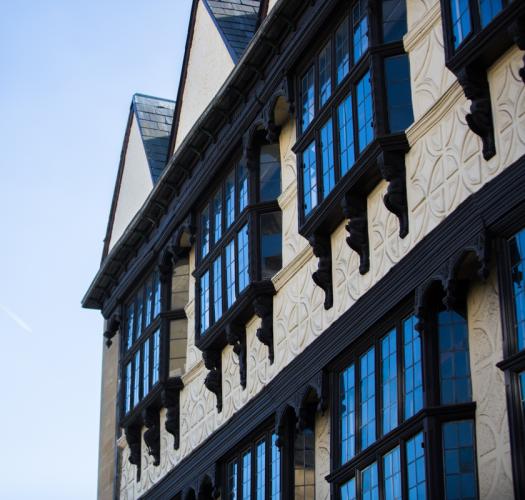 A side-on view of a cream timber frame building with regular black windows.