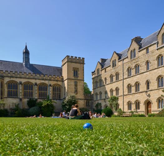 A grassy garden between a large stone college building and a chapel.