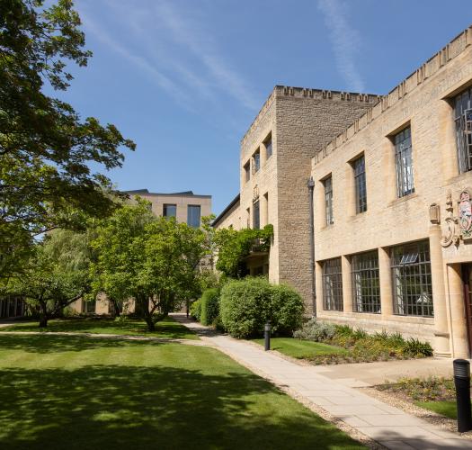 A building with regular rectangular windows and a stone crest above the door set in grassy grounds.