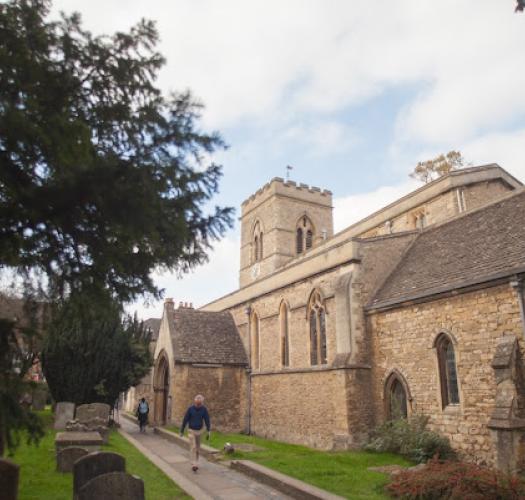 A man walks down a pathway into a churchyard.