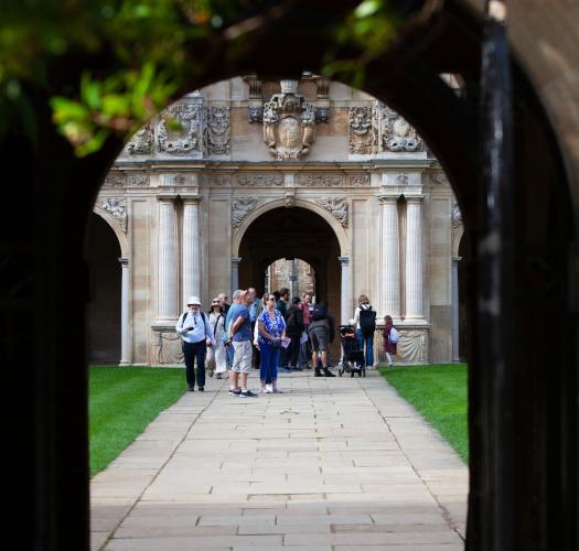 A group of visitors walk through a seventeenth-century quadrangle of an Oxford college.