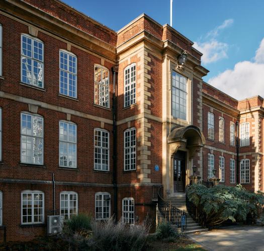A three-storey brick building with regular white frame windows and a carved stone entrance up a flight of stone steps.