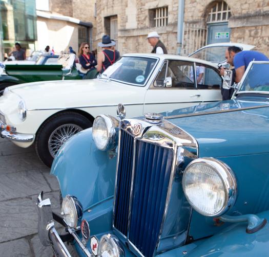 A row of blue, cream and green classic cars parked in from of Oxford Castle and Prison.