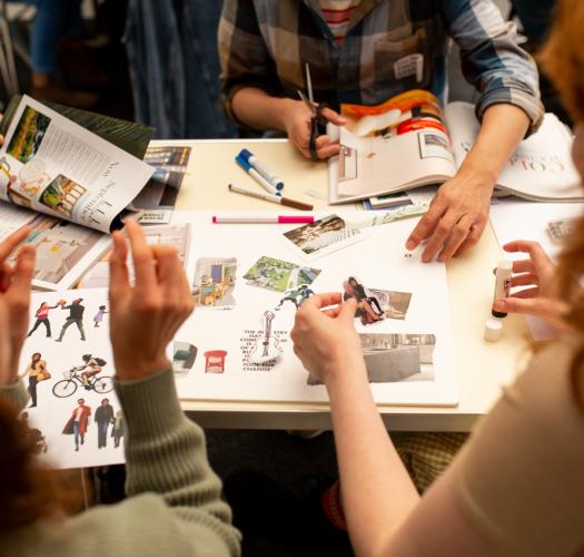 A group of people sitting around a table creating a zine.