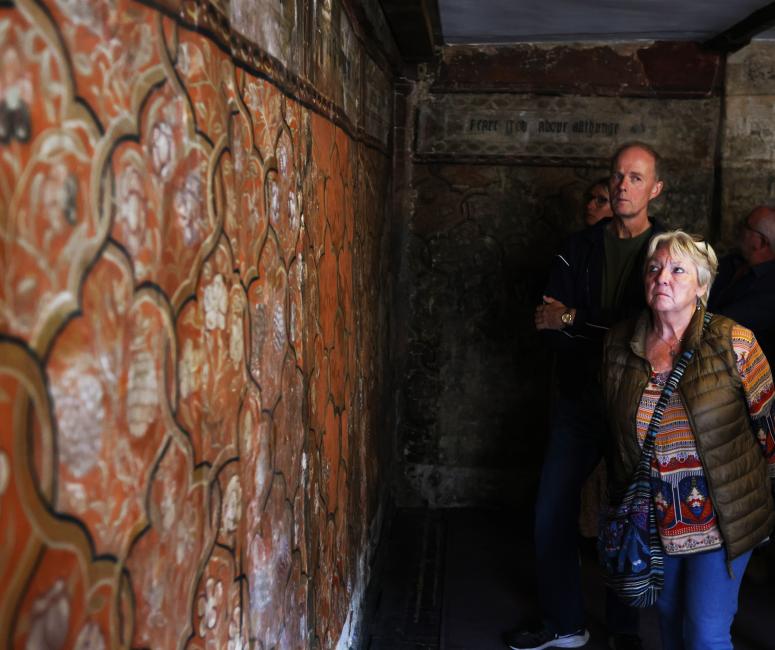 Two people looking at the wall paintings at the painted room