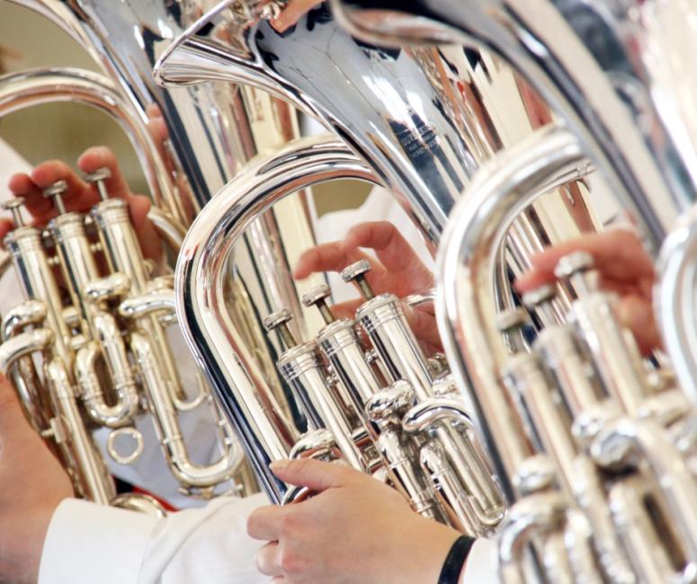 Close-up photograph of three brass instruments being played.