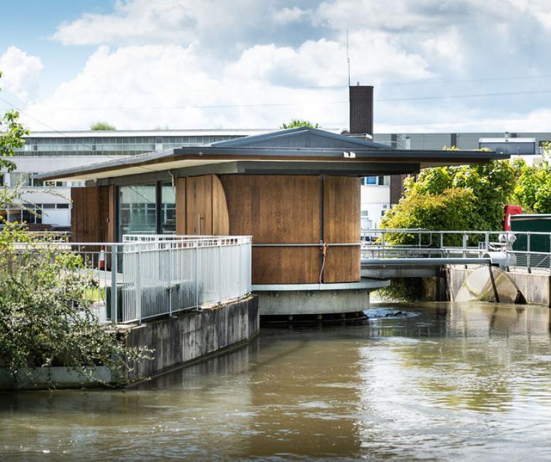 Photo of a low wood-panelled building constructed over a canal.