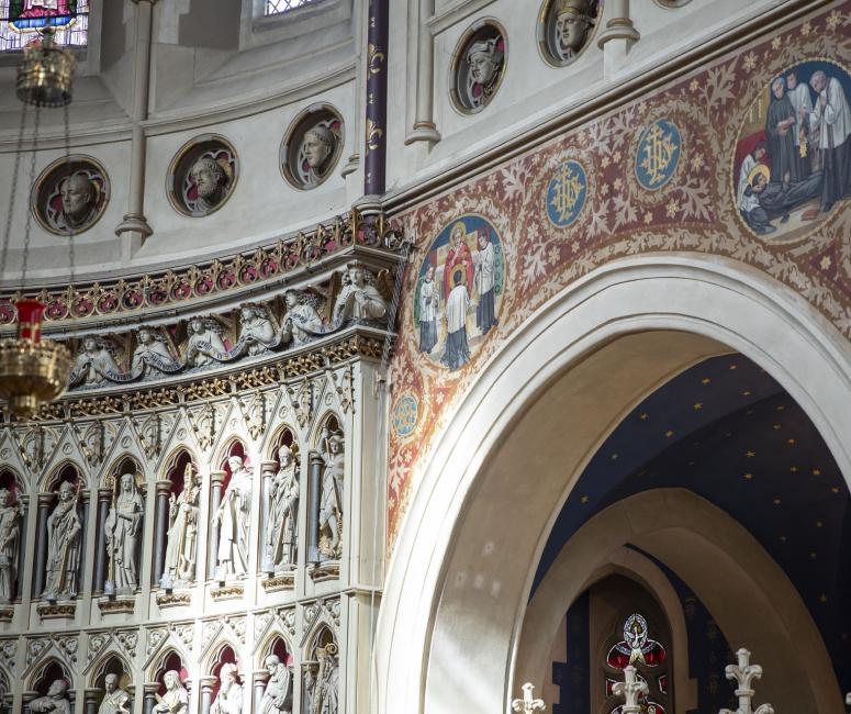 Image of a church interior with wall paintings and a sculpted reredos.
