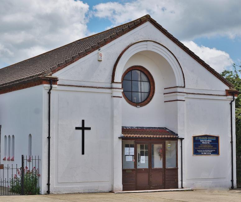 A picture of a white single-storey church building with a circular front window and a brown roof.