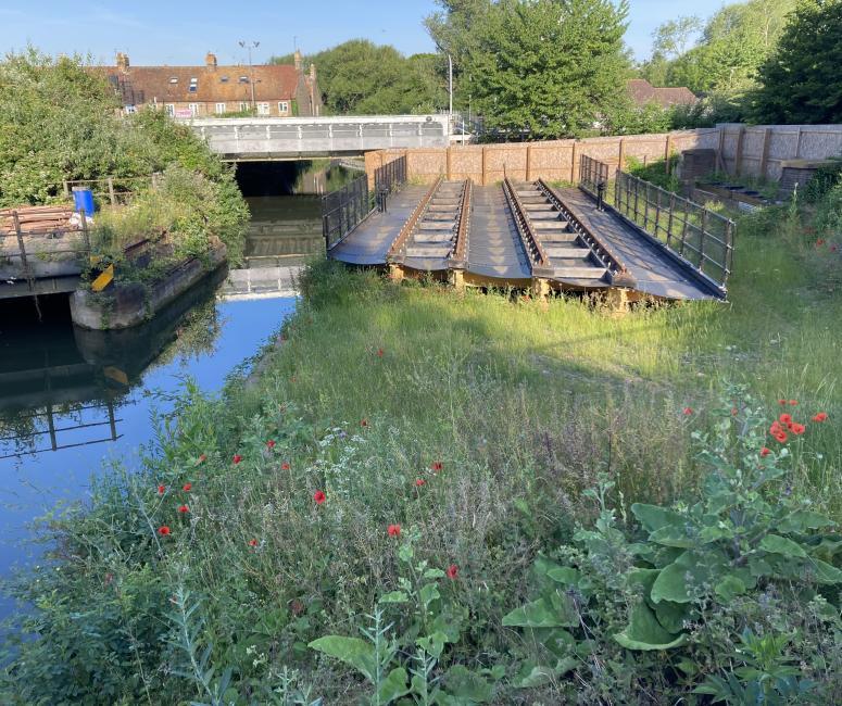 A section of moveable railway bridge in a green area next to a channel of water.