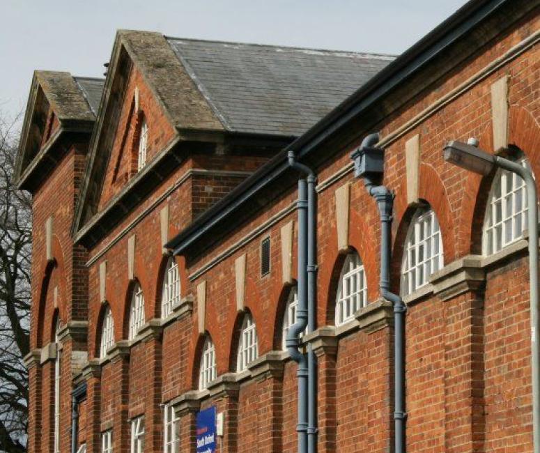 Photograph of a red brick building with semi-circle shaped white windows and a blue sign.