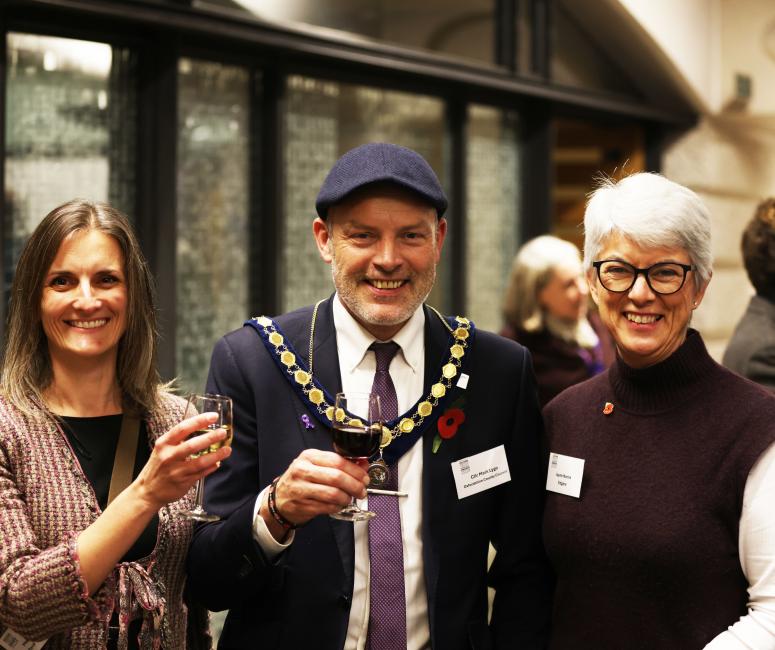 a man wearing a hat and mayoral chain and two women.