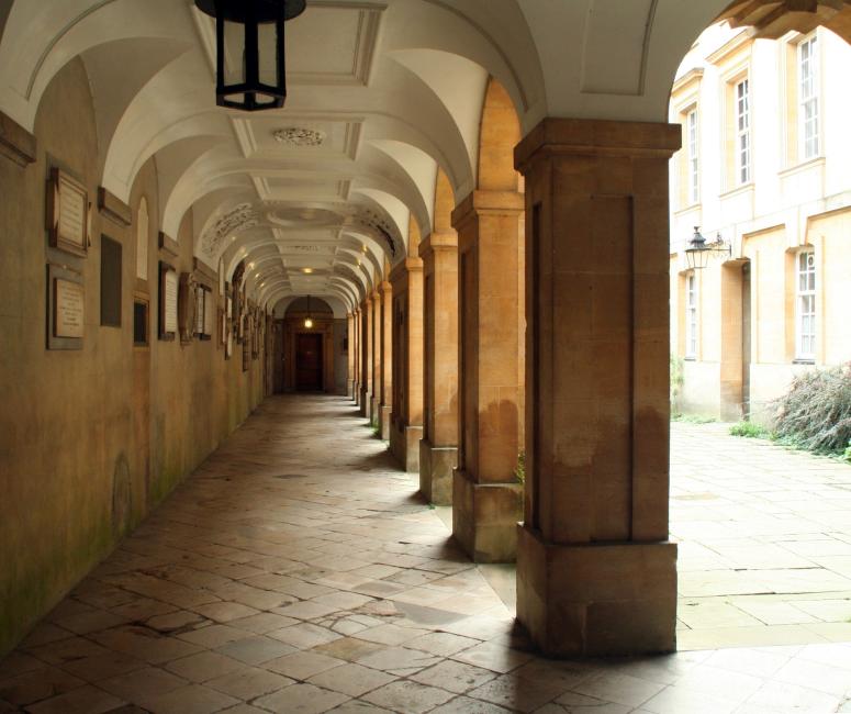 Stone cloisters with a paved floor and ceiling painted white.