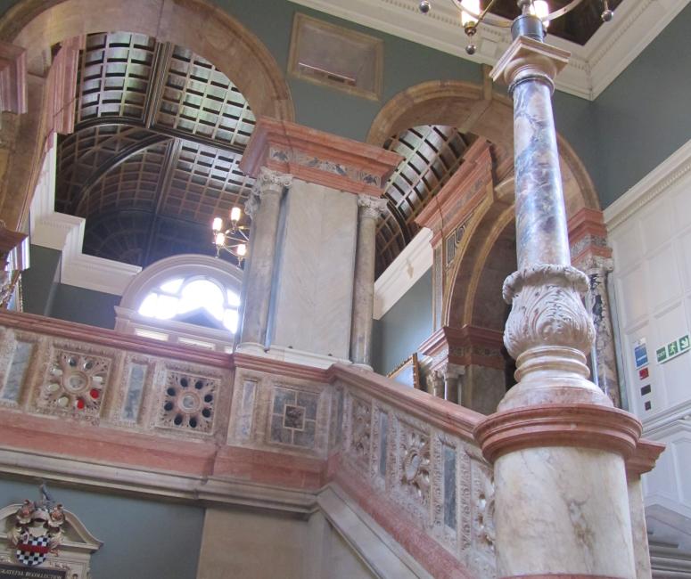 A staircase made from pink and cream marble in a stairway painted pale green.