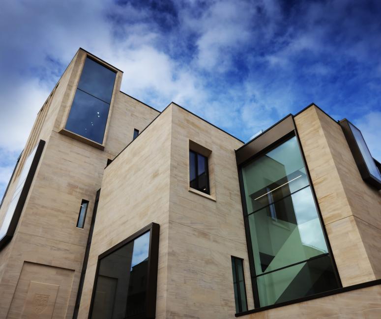 A modern stone building composed of rectangular shapes and right angles, with large rectangular windows or different faces at irregular intervals.