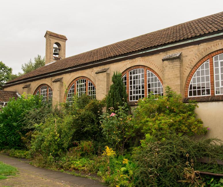 The side view of a one-storey church with semicircular windows and a small bell turret.