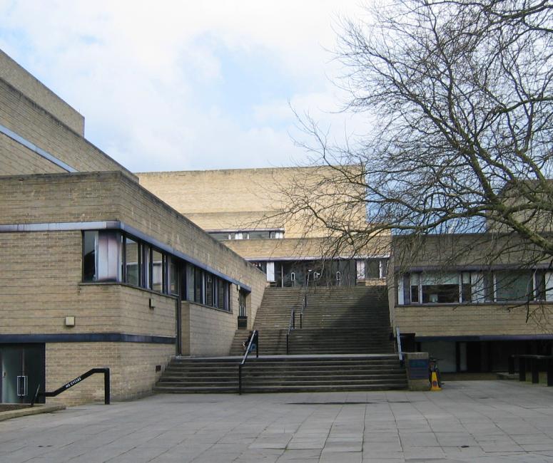 A modern brown brick building with rectangular wings and a long central staircase.