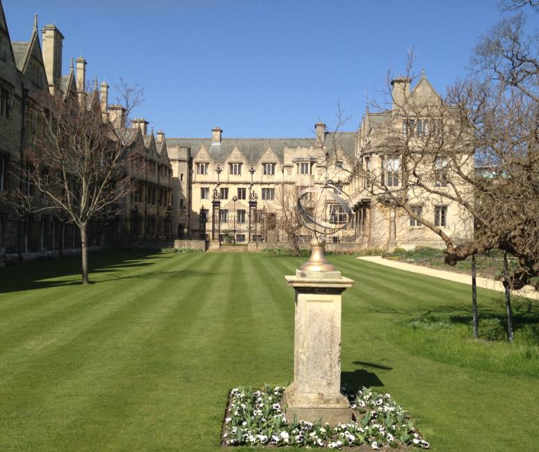 A lawn with a sundial ringed with flowers.