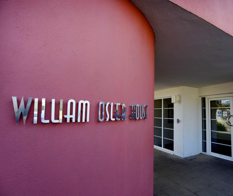 A 1930s building with red painted wall and sign reading William Osler House