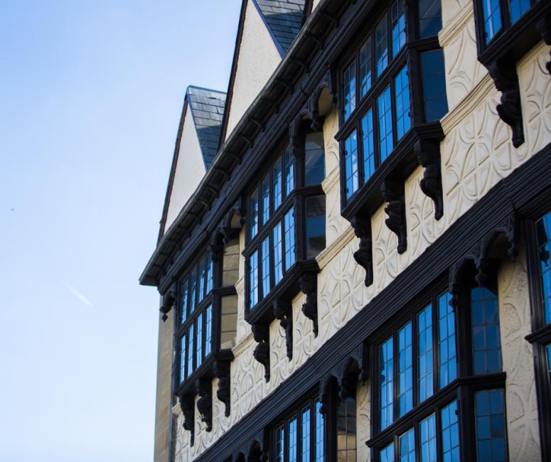 A side-on view of a cream timber frame building with regular black windows.