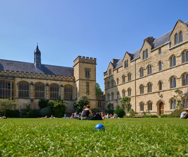 A grassy garden between a large stone college building and a chapel.