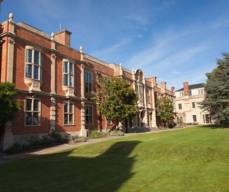A red brick library building with stone bay windows and a large lawn in front.