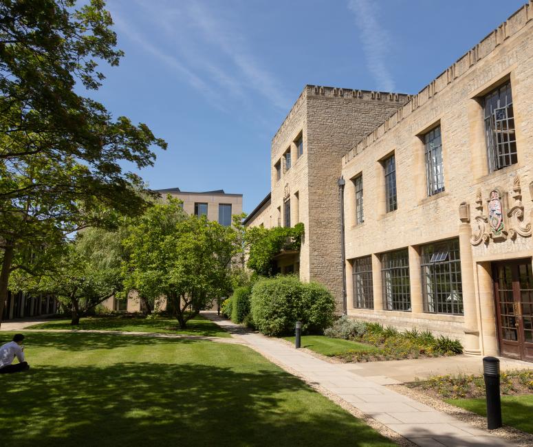 A building with regular rectangular windows and a stone crest above the door set in grassy grounds.
