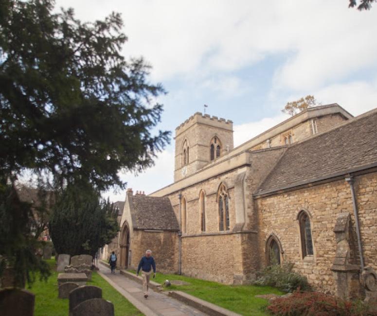 A man walks down a pathway into a churchyard.