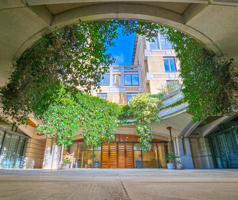 A modern building with a circular skylight with hanging greenery spilling over the edge into the courtyard below.