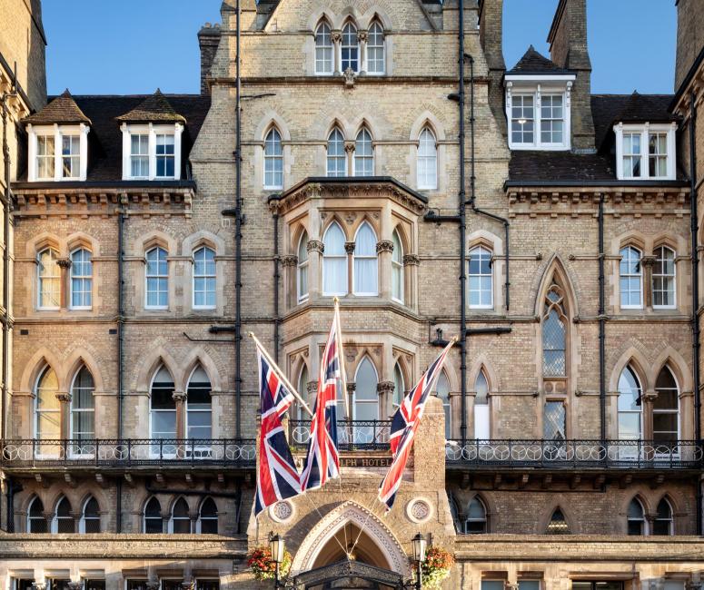 A very large Victorian brick building with three union jacks flying outside an arch doorway.