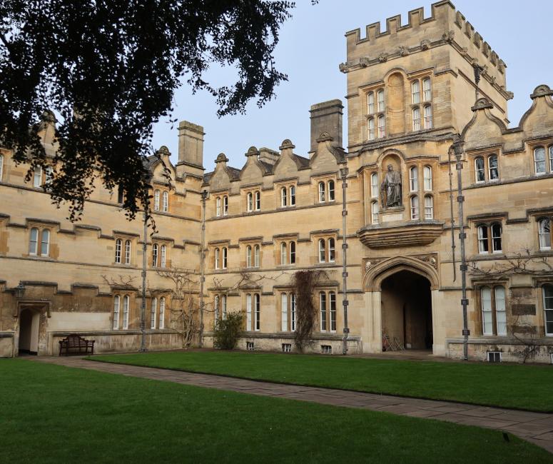 A grassy quadrangle surrounded by large stone buildings including a gatehouse.