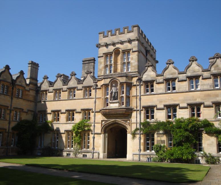 A grassy quadrangle surrounded by large stone buildings including a gatehouse.