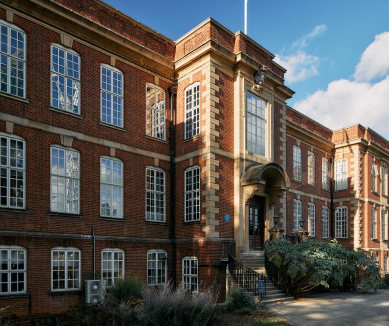 A three-storey brick building with regular white frame windows and a carved stone entrance up a flight of stone steps.