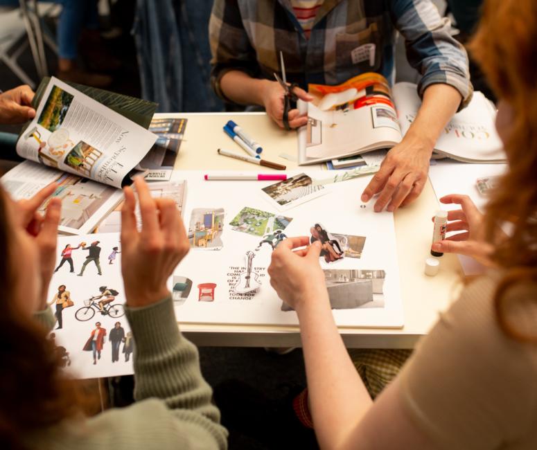 A group of people sitting around a table creating a zine.